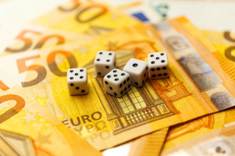 White Gaming dice and money on dark table.